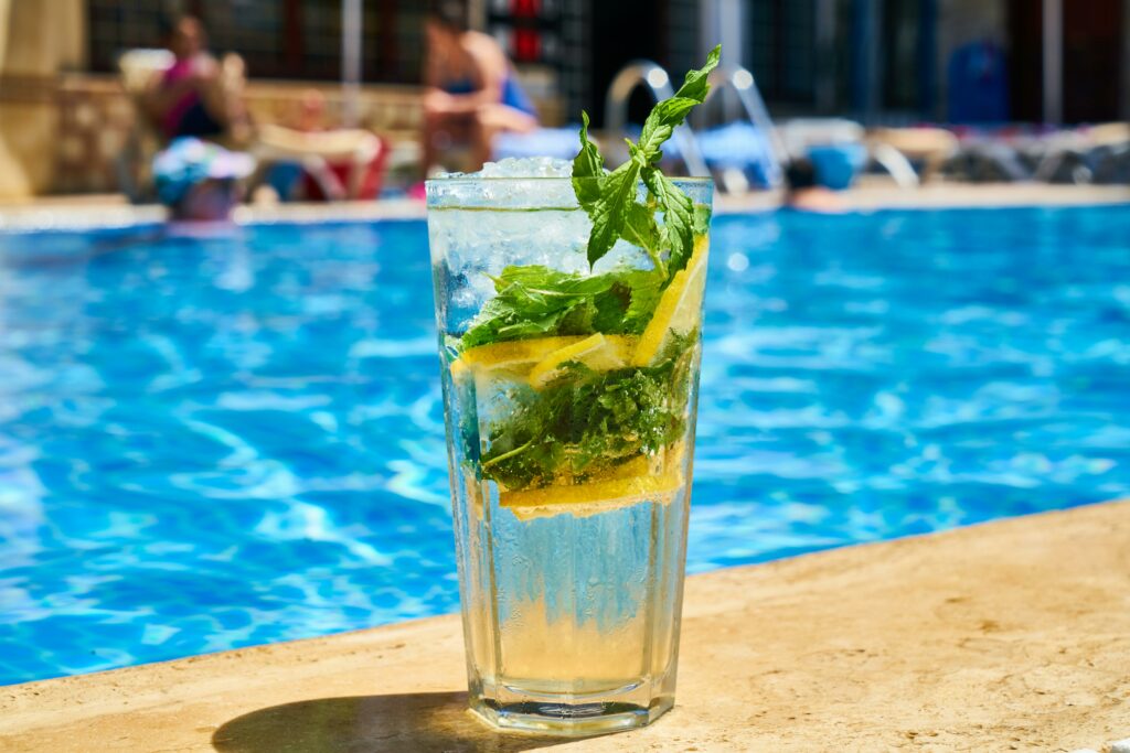 Chilled lemon mint cocktail on a sunny day by the poolside, perfect refreshment for summer.